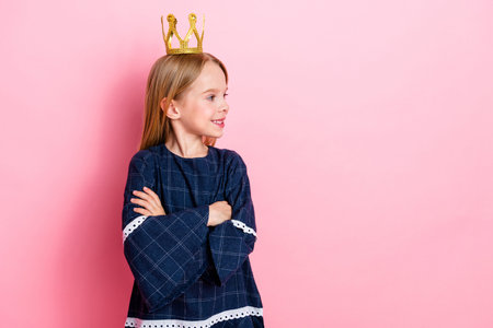 Confident young girl wearing a crown on a pink background showing pride and joy, expressing childhood creativity and funの写真素材