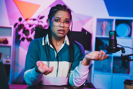 Podcaster female podcaster broadcasting with microphone in neon-lit room, demonstrating expressive gestures and engaged demeanorの写真素材