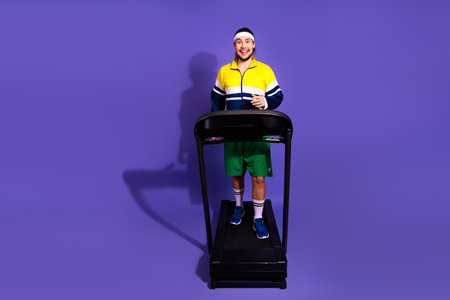 Energetic man exercising on treadmill in retro sportswear against vibrant purple backdrop, promoting...