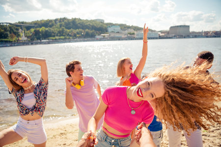 Group of cheerful young friends enjoying a sunny day together on a scenic beach by the lakeの写真素材