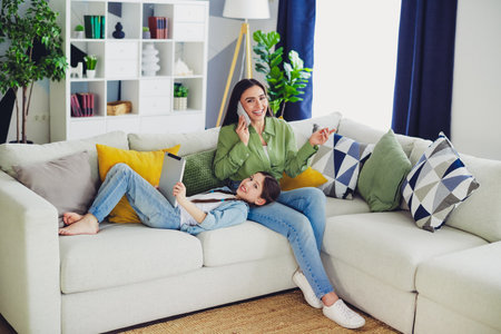 Happy woman with her daughter enjoying a relaxing weekend at home together, showcasing family bonding and modern lifestyle.の写真素材