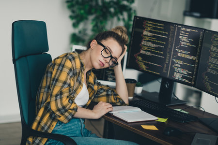 Young female programmer working on code in a casual home office setting showcasing a remote work environmentの写真素材
