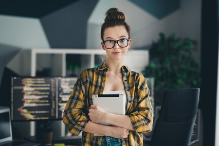Qualified female programmer working on code development in a modern office while holding a tabletの写真素材