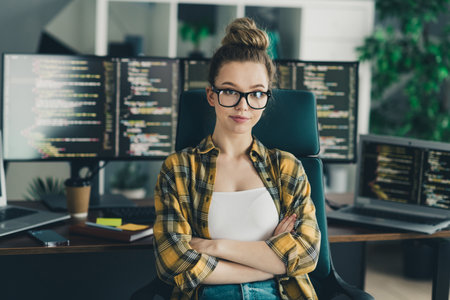 Confident Female Programmer Working Remotely in a Stylish Home Office Equipped With Coding Monitorsの写真素材