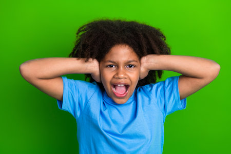 Excited young girl in vibrant mood posing with dramatic gesture against a vivid green background expressing vibrant energyの写真素材