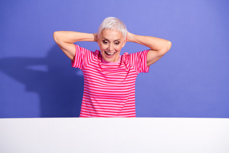 Portrait of a senior woman in a striped t-shirt enjoying a relaxed moment with hands on her head...