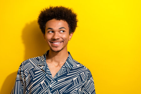 Portrait of a handsome young man smiling against a vibrant yellow background in casual attireの写真素材