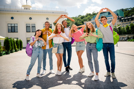 Students forming heart symbols outdoors in urban setting during a sunny day, symbolizing fun and friendshipの写真素材