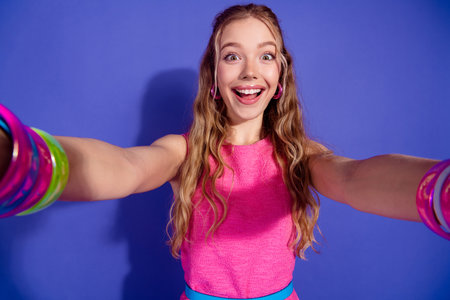 Excited young woman in stylish pink dress against a vibrant purple background, expressing joy and...