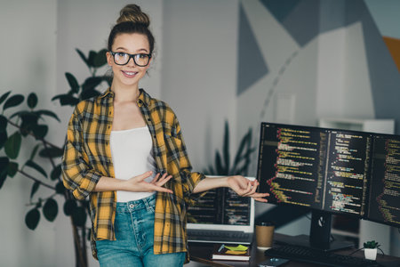 Qualified female programmer presenting coding work at her professional workspace, displaying a modern remote work lifestyleの写真素材