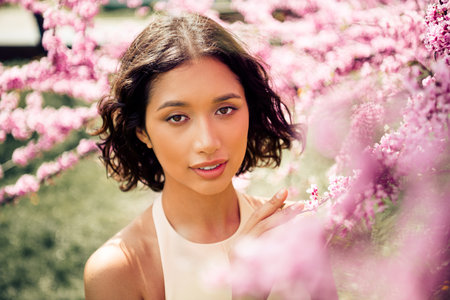 Cute woman enjoying a sunny day surrounded by beautiful pink blossoms in a serene botanical garden...