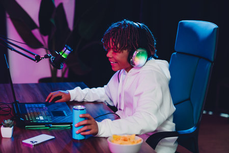 Young male gamer streaming online at night using a professional microphone in a vibrant neon-lit roomの写真素材