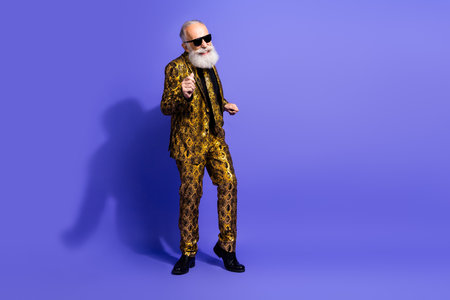 Stylish elderly man with white beard wearing a vibrant patterned suit on a purple background, exuding confidence and charismaの写真素材