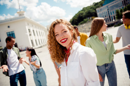 Group of young friends enjoying a sunny day outdoors, sharing laughter and joy in a lively urban...