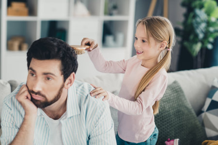 Father and daughter bonding at home as they share a lighthearted moment during a weekend in their cozy apartmentの写真素材