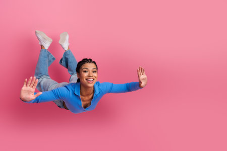 Young woman wearing casual blue top posing on a pink background, expressing joy and positivity with...