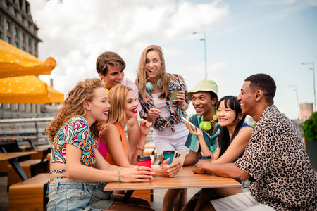 Group of young friends enjoying outdoor moments together at a cafe on a sunny day, sharing laughter...