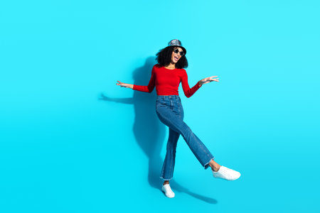 Stylish young woman in a trendy red outfit posing energetically, set against a vibrant blue...