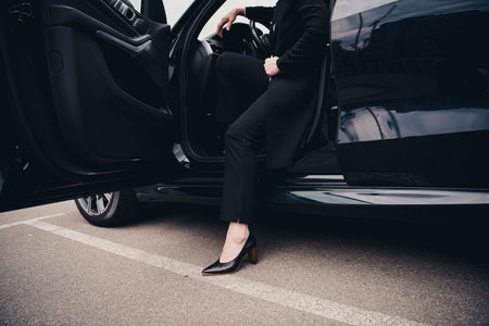 Elegant woman stepping out of a car in an urban setting, exuding professionalism and sophistication in formal clothing.の写真素材