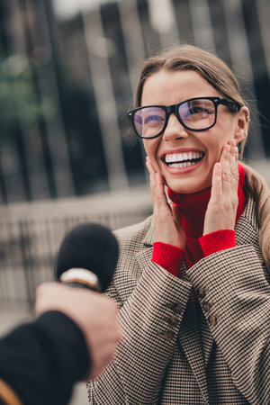 Businesswoman smiling outdoors during an urban interview in spring, highlighting charm and elegance in a city settingの写真素材