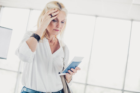 Sad woman at airport terminal analyzing ticket details, expressing confusion and concern before an...