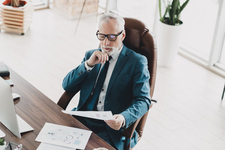 Mature businessman in a professional setting reviewing a strategy documentの写真素材