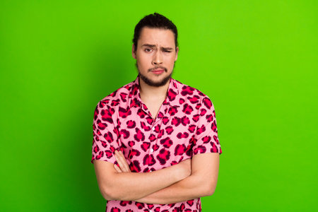 Young fashionable man in stylish leopard print shirt posing confidently against vibrant green backgroundの写真素材