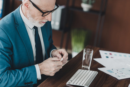 Confident mature businessman working in a modern office workspace and analyzing documents with determinationの写真素材