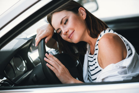 Young woman in stylish attire enjoys a relaxing drive during a sunny dayの写真素材