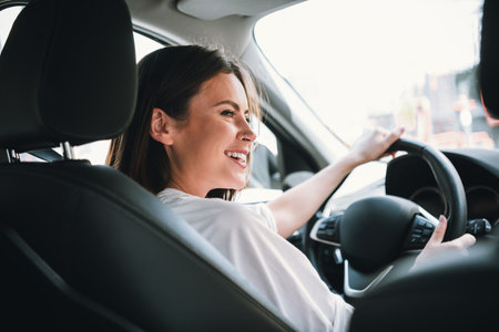 Young woman enjoying a sunny day drive in the city, smiling and experiencing the freedom of the open...