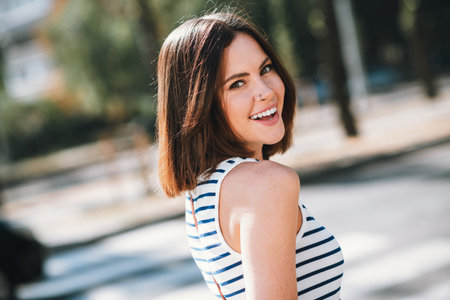 Beautiful young woman enjoying a sunny day in the city wearing a stylish striped shirtの写真素材