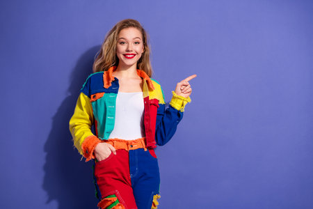 Young woman in colorful fashion outfit gesturing with one hand on vibrant background, showcasing...
