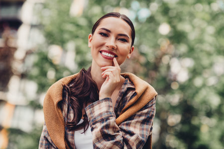 Young stylish woman smiling casually outdoors in an urban park setting on a sunny autumn dayの写真素材