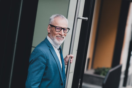 Confident mature businessman in formal suit outdoors in an urban setting, showcasing success and...