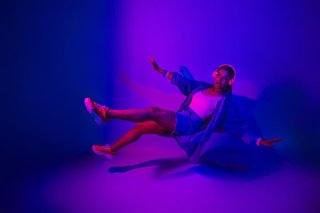 Lovely fashionable woman posed under neon lighting wearing stylish clothing in vibrant studio atmosphereの写真素材