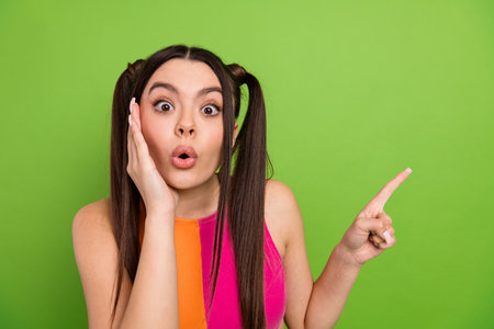 Young stylish woman with a surprised expression against green background, vibrant and trendy look for modern visualsの写真素材