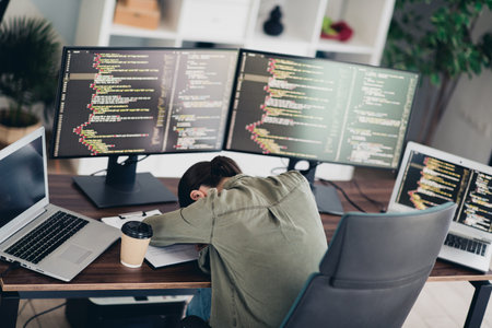Charming professional female programmer working remotely with multiple monitors and laptops