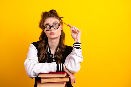 Curious and playful young woman in casual style posing with book against yellow background