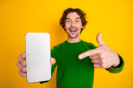 Happy man in vibrant outfit displaying smartphone with blank screen, showcasing advertising or app...