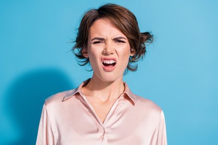 Young woman expressing confusion and surprise with a quirky grimace on her face against a vibrant...