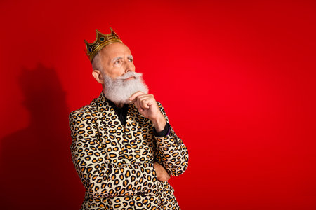 Charismatic senior man in a leopard print suit and crown against a red backdrop, embodying style and...