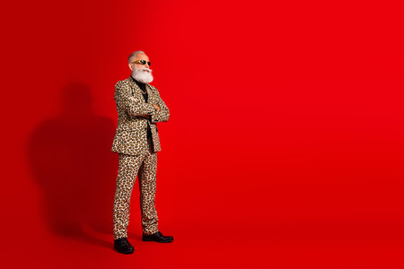 Fashion model in stylish leopard suit posing confidently in front of vibrant red background, exuding charm and eccentric fashion senseの写真素材