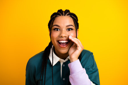 Optimistic woman with braided hair and vibrant casual outfit making an exciting gesture on a bright...