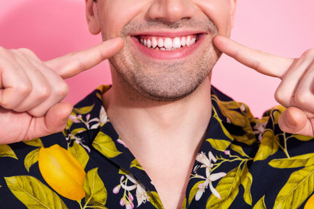 Closeup of a young man smiling with vibrant tropical shirt and cheerful expression against a pink...