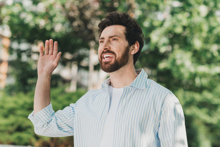 Cheerful man in casual attire enjoying a sunny day outdoors with a friendly expression and a charming smileの写真素材