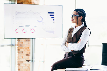 Confident businesswoman presenting analytics in a corporate environment, showcasing graphs on a...