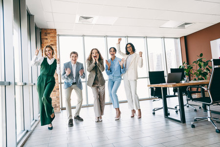 Excited business colleagues celebrating success in a modern office teamwork achievement environmentの写真素材