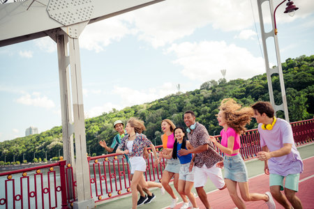A cheerful group of young friends enjoying a fun adventure on a sunny day outdoors in a vibrant urban cityscapeの写真素材