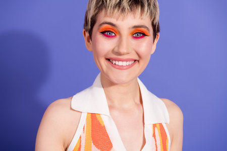 Smiling Young Model with Colorful Makeup and Stylish Short Hair on a Vibrant Purple Background