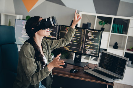 Young woman interacting with virtual reality while working on programming in a modern office setting